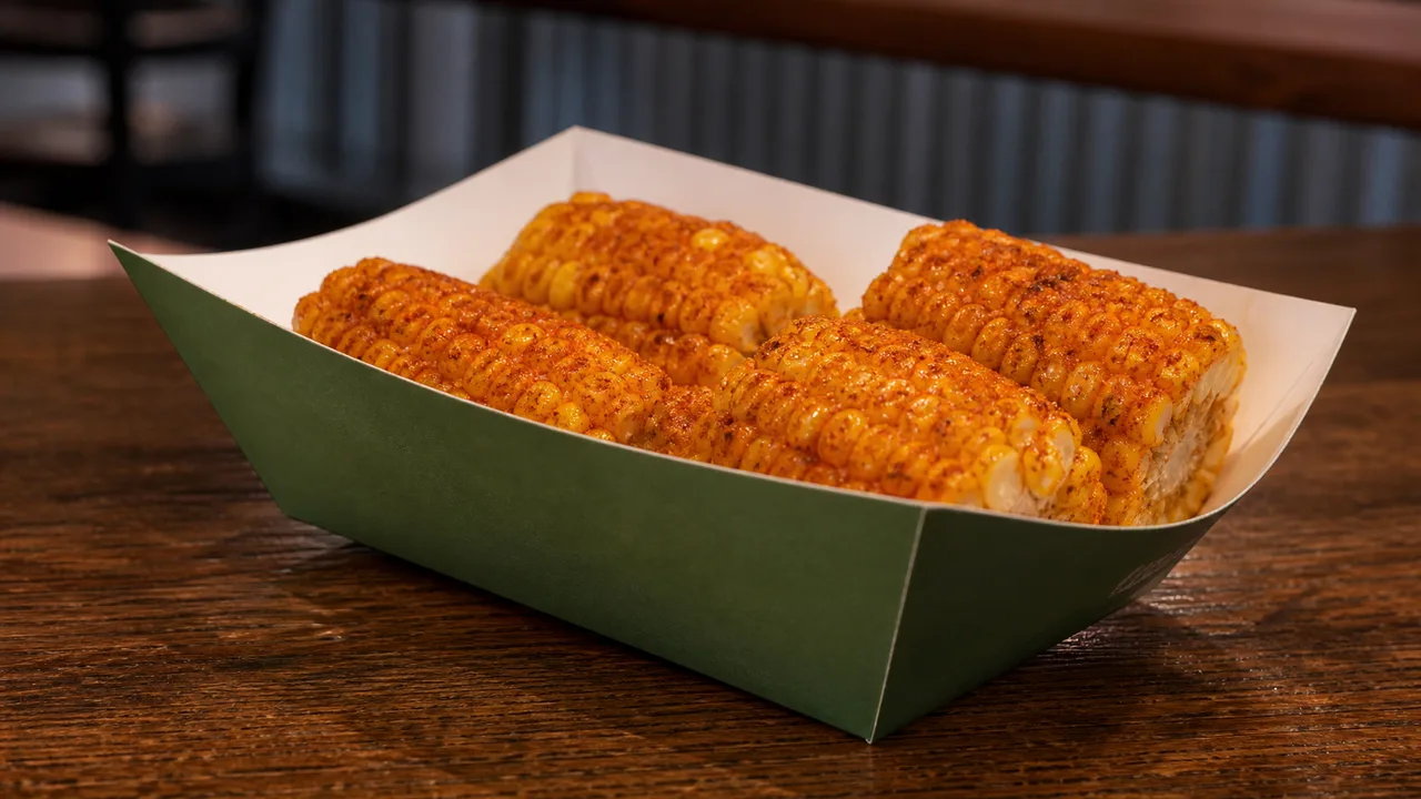 Cajun-seasoned fried corn cob segments in a green paper food boat