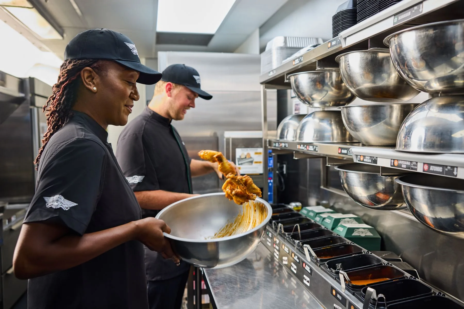 Wingstop team member tossing wings in sauce